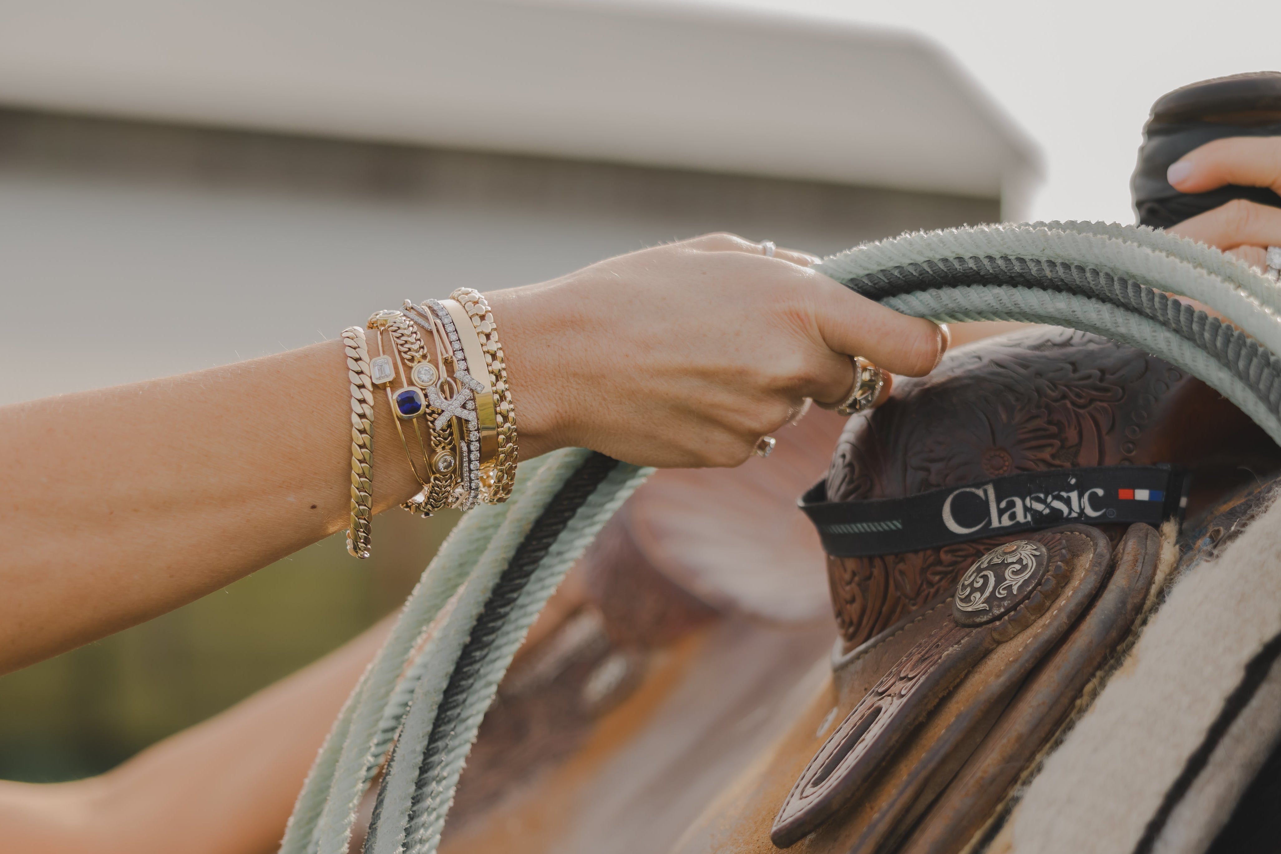 Close-up of a hand holding a rope on a saddle with a blurred background