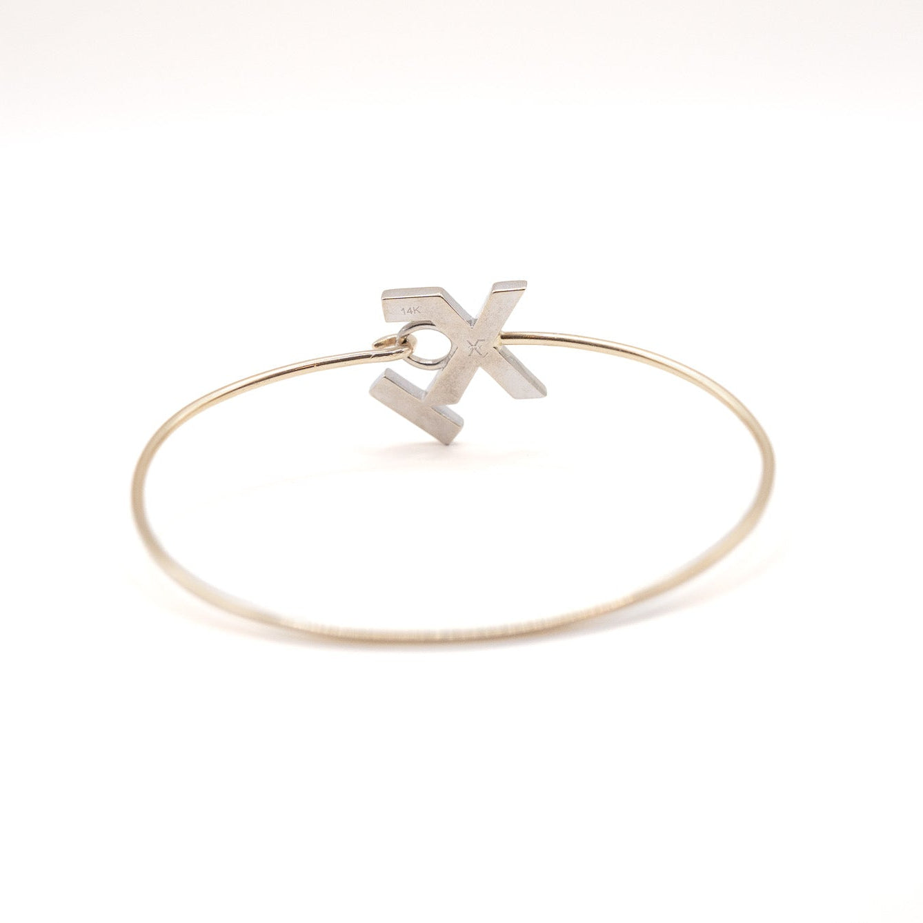 Gold bracelet with a 'X' charm on a white background