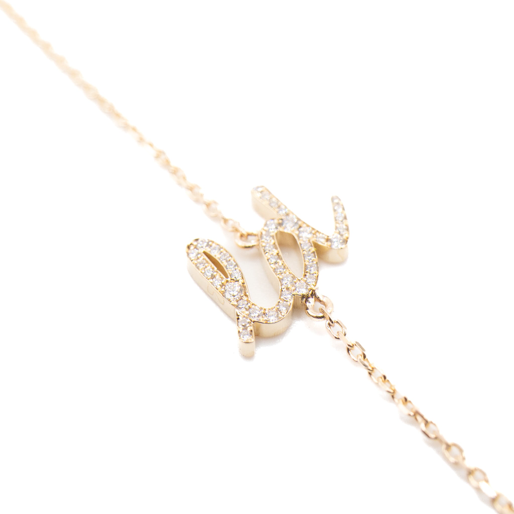 Gold necklace with a diamond-encrusted pendant on a white background